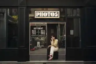 Woman sitting in phone booth outside store.