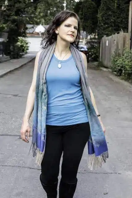 A woman walking on a suburban street dressed casually with a scarf, home, relaxed style, confident walk.