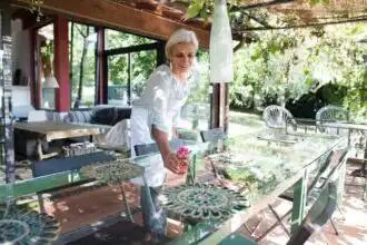 Beautiful senior woman setting a table outdoors in a lush garden.