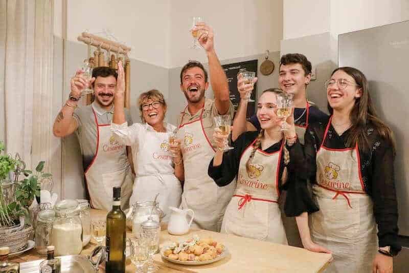 Cheers, friends celebrating with wine in a warm kitchen atmosphere.