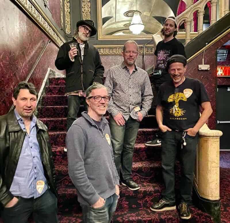 Group of men on ornate red staircase at Divine Magazine gathering.