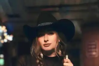 Elegant woman in black cowboy hat with braids showcasing Western fashion vibe.