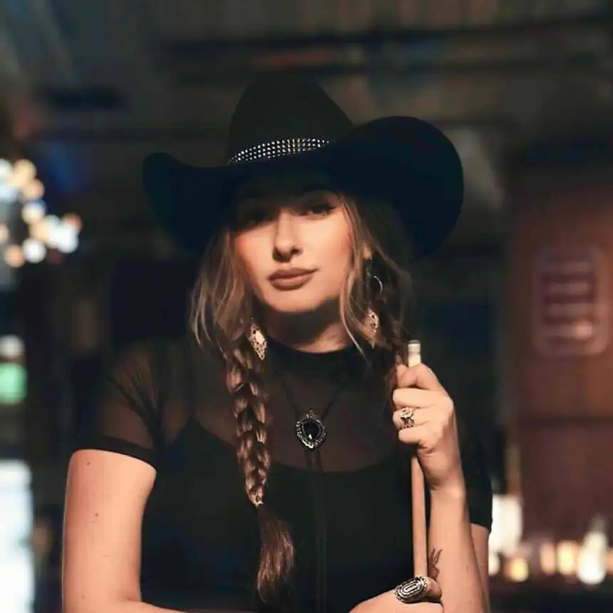 Elegant woman in black cowboy hat with braids showcasing Western fashion vibe.