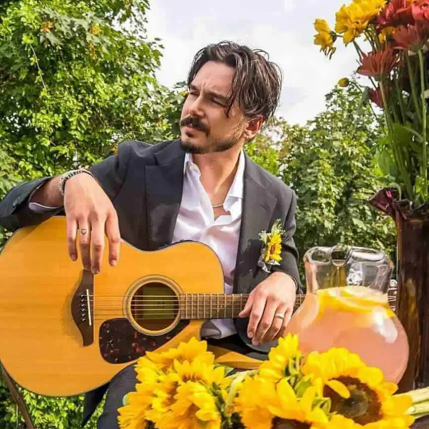Outdoor garden scene with man playing guitar, surrounded by colorful flowers and lush greenery.