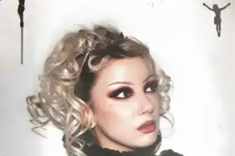 Gothic woman with platinum curly hair, bold makeup, and black lace choker for alternative fashion.