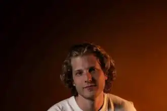 Portrait of a confident young man in casual white t-shirt and jeans, warm lighting, dark background.