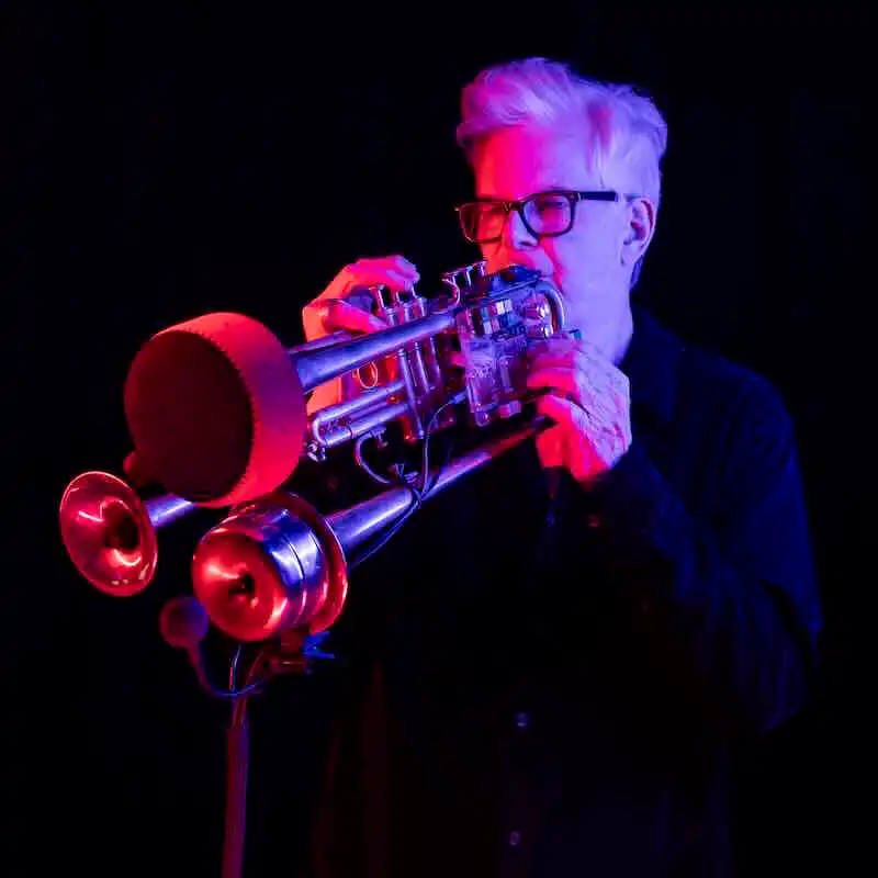 Jazz musician playing trumpet with colorful stage lighting.
