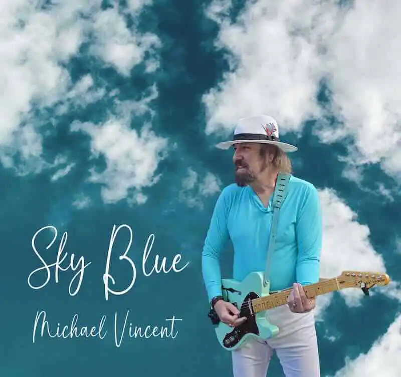 Man playing guitar under blue sky with clouds, music, LGBTQ, and pride themes.