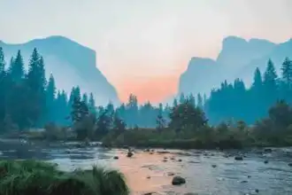 Beautiful mountain river landscape at sunrise with lush trees and distant mountains.