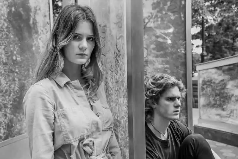 Young woman and man sitting apart in a modern bus stop, conveying youth, loneliness, and emotional distance.