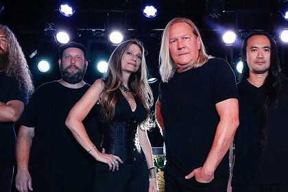 Alt text: A diverse heavy metal band performing on stage with dramatic lighting and energetic presence.