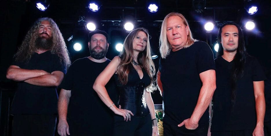 Alt text: A diverse heavy metal band performing on stage with dramatic lighting and energetic presence.