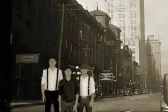 Vintage urban street scene with three men, historic buildings, and city vehicles.
