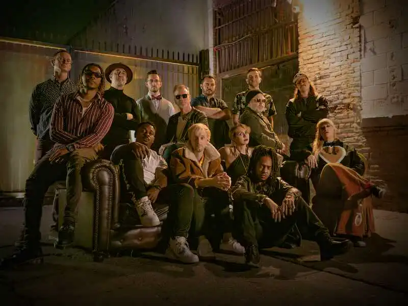 Diverse group of people poses together in urban setting for Divine Magazine article on LGBTQ+ representation.