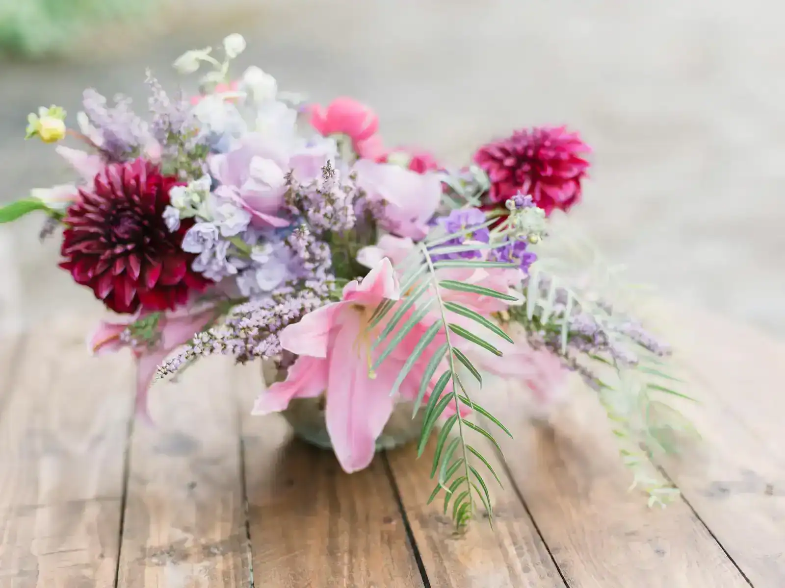 Vibrant bouquet of assorted flowers elegantly arranged on a rustic wooden table.