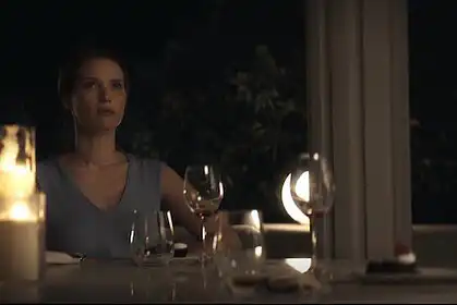 Elegant woman enjoying wine tasting at night with candles and glasses.