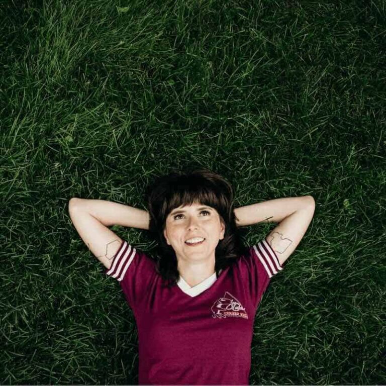 Ellie Heath – Pushing Forty (New Single & Album Announcement) Ellie Heath lying on grass with arms behind head, smiling.
