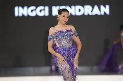 Elegant model in purple evening gown walking on runway during fashion show.