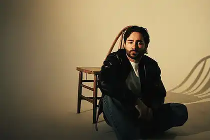 Ike Dweck seated on a chair with a neutral background, promoting his new single and US tour 2026.