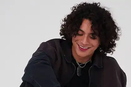 Frankie with curly hair smiling, celebrating new single "R0LL3RC0AST3R".