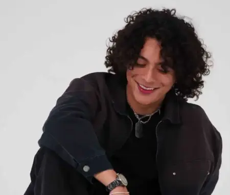 Frankie 5Ø3 Delivers Nostalgic New Single “R0LL3RC0AST3R” Frankie with curly hair smiling, celebrating new single "R0LL3RC0AST3R".