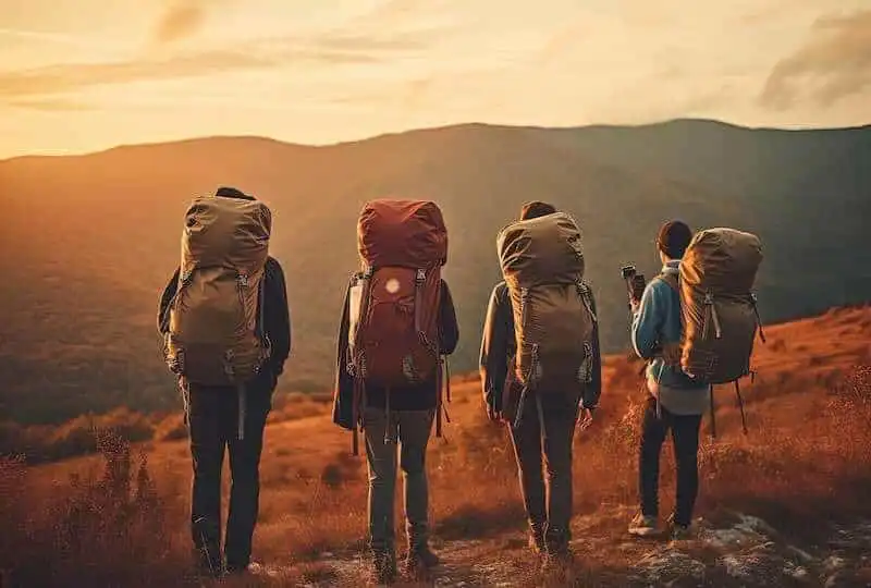 Hikers with large backpacks exploring mountain trail at sunset, outdoor adventure, travel, wilderness exploration.