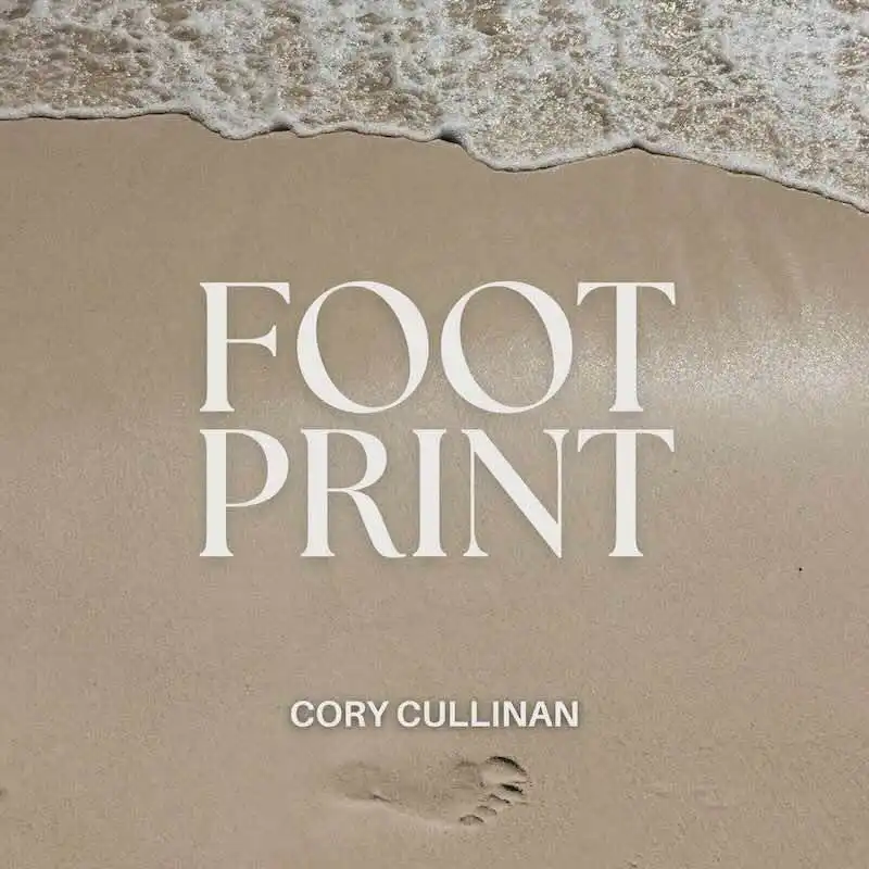 Alt text: Beach shoreline with footprints, gentle waves, and sandy surface.