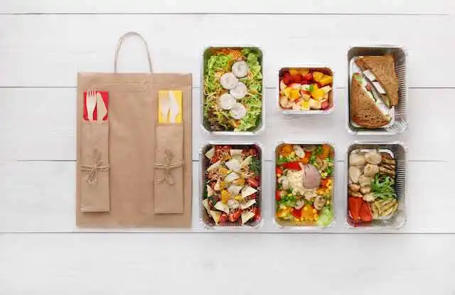 A variety of freshly prepared salads and sandwiches in eco-friendly containers for meal prep.
