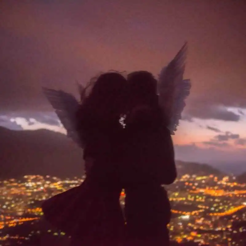 Romantic silhouette with angel wings at sunset.