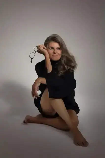 Thoughtful woman with glasses, casual pose, neutral background for lifestyle and fashion stories.