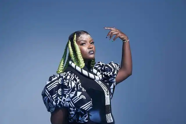 Diverse LGBTQ+ woman with vibrant green braids, stylish clothing, and confident pose, representing empowerment and identity.